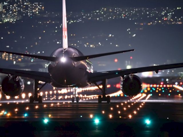 A commercial airplane on a runway at night with city lights in the background.