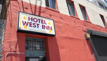 The image shows the exterior of a building with a sign that reads “Hotel West Inn” and an address number 1617 above a gray door, ending the sentence.